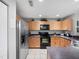 Well-equipped kitchen boasts black appliances, light wood cabinets, ample counter space, and stainless steel refrigerator at 3071 Seaview Castle Dr, Kissimmee, FL 34746