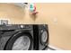 This laundry room includes a front load washer and dryer set with overhead shelving at 308 Yellow Snapdragon Dr, Davenport, FL 33837