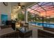 Spacious covered patio with mini-fridge and comfortable lounge seating next to a screened pool enclosure at 308 Yellow Snapdragon Dr, Davenport, FL 33837