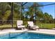 Relaxing lounge chairs sit poolside within a screened enclosure overlooking the landscaped backyard at 308 Yellow Snapdragon Dr, Davenport, FL 33837