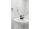 Close-up of a pedestal sink with modern black fixtures and a round mirror in a bright bathroom at 3765 Deer Ridge Dr, Mount Dora, FL 32757
