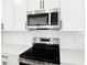 Modern kitchen featuring stainless steel microwave and oven against a white backsplash and countertop at 3765 Deer Ridge Dr, Mount Dora, FL 32757