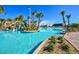 Community pool with a slide and a large pool area surrounded by palm trees and lounge chairs at 9042 Stinger Dr, Davenport, FL 33896