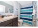 Well-lit bathroom featuring a vanity with granite countertop, a mirror, and a blue-striped shower curtain at 9056 Wildflower Ln, Kissimmee, FL 34747