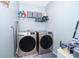 Functional laundry room equipped with modern washer and dryer units, plus shelving for storage at 9056 Wildflower Ln, Kissimmee, FL 34747