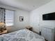 A bedroom with a mounted TV, white dresser, and a window allowing for natural light at 925 Montana Ave, Davenport, FL 33897