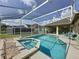 A screened-in pool and jacuzzi with tiled trim surrounded by ample lounge area, patio, and green grass at 925 Montana Ave, Davenport, FL 33897