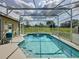 A screened-in pool and jacuzzi with tiled trim surrounded by lush green grass at 925 Montana Ave, Davenport, FL 33897