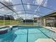 A screened-in pool and jacuzzi, alongside covered patio, complete with neutral tiled trim and lush green grass at 925 Montana Ave, Davenport, FL 33897