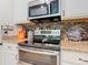 Close-up of a modern kitchen with a stainless steel oven and microwave, granite countertops, and tile backsplash at 105 Palazzo Ln, Kissimmee, FL 34759