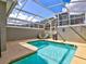 Backyard pool features turquoise water, seating and grilling area in a screened enclosure at 1058 Splash Shot Pl, Davenport, FL 33896