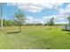 Expansive backyard with a vibrant green lawn and scattered trees under high-voltage electric lines, with a white fence at 12379 Turtle Grass Dr, Orlando, FL 32824