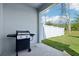 Covered patio with concrete flooring featuring a grill for outdoor cooking, a white fence, and a grassy area at 12379 Turtle Grass Dr, Orlando, FL 32824