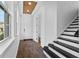 Welcoming foyer with dark wood-look flooring, a staircase, and view of a half-bath at 13282 Bromborough Dr, Orlando, FL 32832