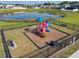 Elevated view of community playground with colorful structure, benches, fencing, and pond at 1379 Winter Gray Cir, Deltona, FL 32738