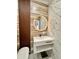 Stylish bathroom with modern floating vanity, illuminated round mirror, and unique wood slat accent wall at 1407 Water Lilly Ln, Kissimmee, FL 34744
