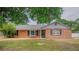 Charming brick home featuring black shutters and a well-maintained front yard, shaded by a mature tree at 1700 E Clinton Dr, St Cloud, FL 34769
