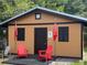 Hurricane shelter exterior featuring a classic gable roof, shutters, and outdoor chairs on the patio at 1849 Kings Point Blvd, Kissimmee, FL 34744