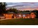Beautifully lit home with a metal roof and manicured landscaping at dusk at 1849 Kings Point Blvd, Kissimmee, FL 34744