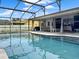 Sparkling blue pool in a screened-in enclosure, travertine deck, covered patio, and seating area at 1849 Kings Point Blvd, Kissimmee, FL 34744