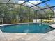 Enclosed pool area with blue water, travertine decking, and lush landscaping in the background at 1849 Kings Point Blvd, Kissimmee, FL 34744