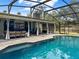 Inviting screened-in pool with sparkling blue water, travertine deck, covered patio and outdoor seating at 1849 Kings Point Blvd, Kissimmee, FL 34744