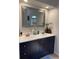 Modern bathroom features dual sinks, a large decorative mirror, and stylish dark blue cabinets at 1920 Triumfo Cir, Kissimmee, FL 34744
