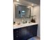 Bathroom features dual sinks with granite countertops, a dark vanity, a decorative mirror, and modern fixtures at 1920 Triumfo Cir, Kissimmee, FL 34744