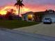 Charming single-story home with a well-manicured lawn, swaying palm tree, and a picturesque sunset backdrop at 1920 Triumfo Cir, Kissimmee, FL 34744
