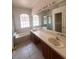Bright bathroom with double sinks, a large mirror, and garden tub beneath an arched window at 1948 Bridgeview Cir, Orlando, FL 32824