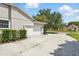 Side exterior showcasing a two-car garage with a long driveway and manicured bushes at 2374 Eagle Trace Dr, Kissimmee, FL 34746