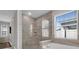 Beautifully tiled bathroom featuring a glass-enclosed shower and a luxurious soaking tub by a window at 2487 Empress Dr, Kissimmee, FL 34741