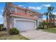 Two-story home with a tile roof, attached garage, and manicured lawn with palm trees and small shrubs at 301 Rosso Dr, Davenport, FL 33837