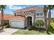 Beautiful two-story home featuring a tile roof, arched entryway, palm trees, and a well-maintained front lawn at 301 Rosso Dr, Davenport, FL 33837