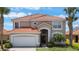 Beautiful two-story home featuring a tile roof, arched entryway, palm trees, and a well-maintained front lawn at 301 Rosso Dr, Davenport, FL 33837
