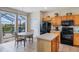 Traditional kitchen with wood cabinets, black appliances, island, and a view to an outdoor, screened lanai at 301 Rosso Dr, Davenport, FL 33837
