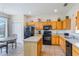 Traditional kitchen features wood cabinets, black appliances, and eat-in dining space with view of screened lanai at 301 Rosso Dr, Davenport, FL 33837