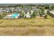 Aerial view of a community pool, playground, fenced dog park, and parking area surrounded by lush trees at 318 Highland Meadows Dr, Davenport, FL 33837