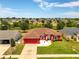 Single-story red home with a well-manicured lawn, a long driveway, and a matching detached garage to the left at 318 Highland Meadows Dr, Davenport, FL 33837