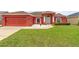 Beautiful exterior view with a lush green lawn, red facade, and attached garage at 318 Highland Meadows Dr, Davenport, FL 33837