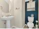 Well-lit half bathroom featuring a pedestal sink, toilet, and decorative wall cabinet at 3881 Wind Dancer Cir, St Cloud, FL 34772