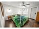 Cozy bedroom with hardwood floors, white walls, a ceiling fan, and a green leaf-patterned blanket at 415 Florida Ave, St Cloud, FL 34769