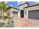 Home's exterior featuring stone accents, a brick driveway, and mature landscaping at 433 Via Abruzzi St, Kissimmee, FL 34759