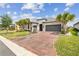 Charming home boasts a well-manicured lawn, palm trees, brick driveway, and a two-car garage at 433 Via Abruzzi St, Kissimmee, FL 34759