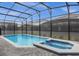 Sparkling pool and jacuzzi surrounded by a screened-in enclosure with brick pavers at 4473 Kaipo Rd, Davenport, FL 33897