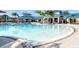 Resort style pool with lounge chairs, palm trees and umbrellas with clubhouse in the background at 4473 Kaipo Rd, Davenport, FL 33897