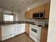 A view of the kitchen that includes a microwave, stove, sink, dishwasher, and wood cabinets at 4726 Hemingway House St, Kissimmee, FL 34746