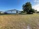 Rear view of a white home with large backyard and mature tree, offering privacy at 505 Peace Way, Poinciana, FL 34759