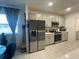A contemporary kitchen featuring stainless steel appliances, sleek gray cabinets, and tile flooring, providing ample space at 505 Peace Way, Poinciana, FL 34759