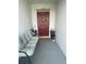 Cozy front porch featuring a gray cushioned seat and red door decorated with a wreath at 505 Peace Way, Poinciana, FL 34759